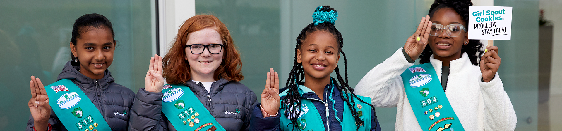  portrait of ambassador girl scout wearing vest and smiling at camera in front of a brick building 